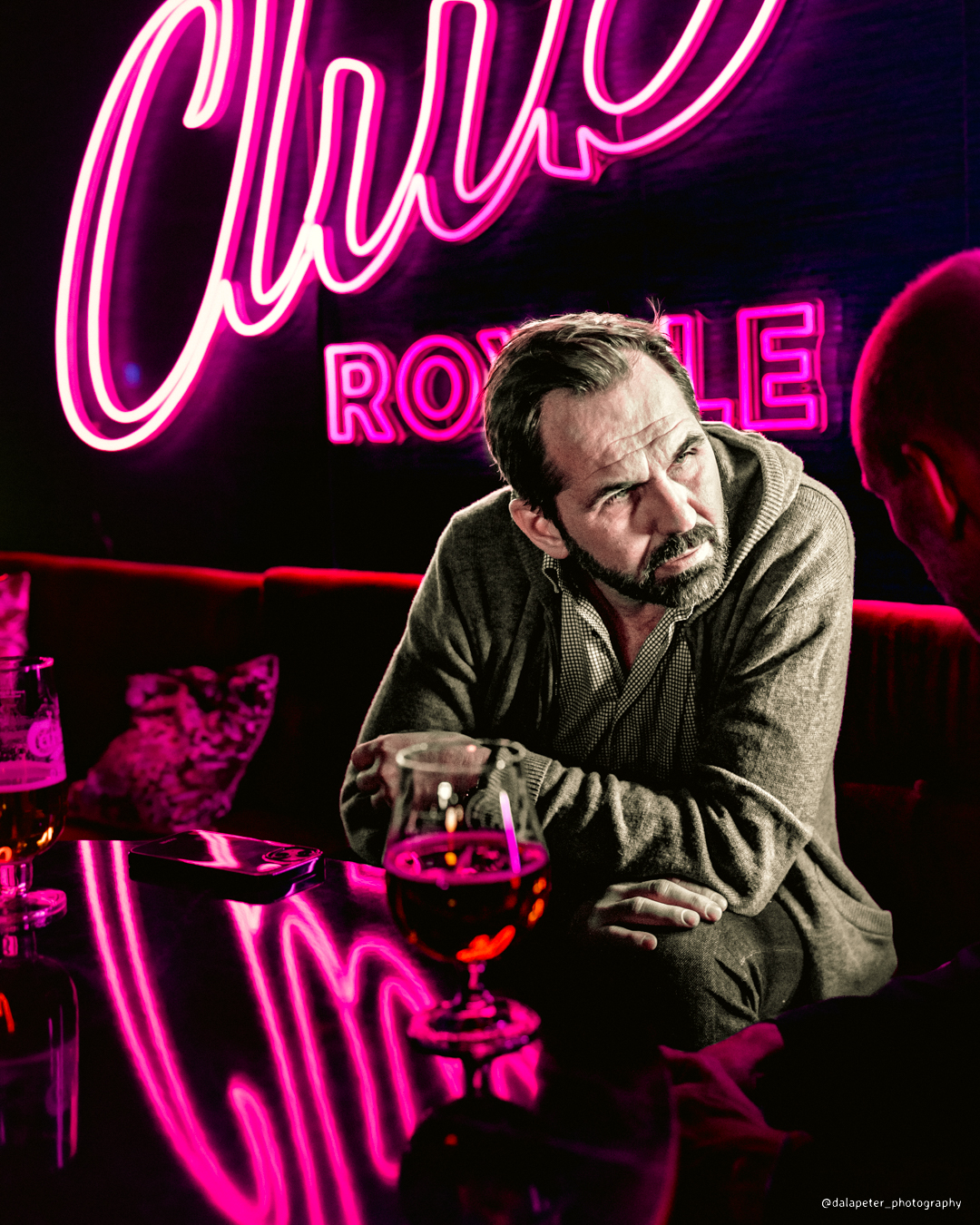 En stylad bild av en man sittandes i neonsken vid ett bord på en nattklubb. Foto: Peter Gunnebro, Dalapeter Photography